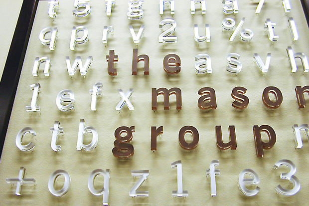 Raised acrylic with metal effect office signage reflecting light and casting shadow on reception area wall - Art Signs Company