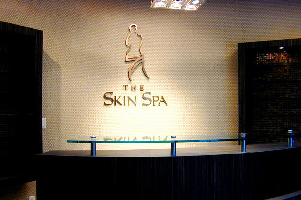 Office reception area sign made with laser cut 3D acrylic and copper metal letters and symbols raised off the wall on stand offs.
