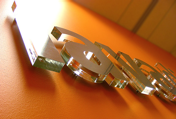 Corporate logo sign with brushed metal finish to match stainless steel look, waiting area wall installation