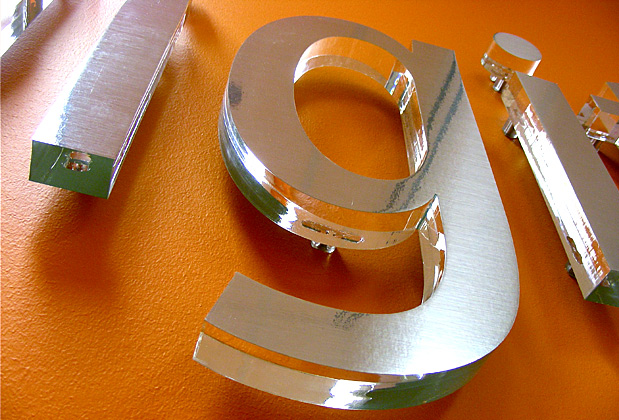 Corporate logo sign with brushed metal finish to match stainless steel look, waiting area wall installation
